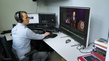 Man at desk moving mouse while looking at video files on a desktop machine