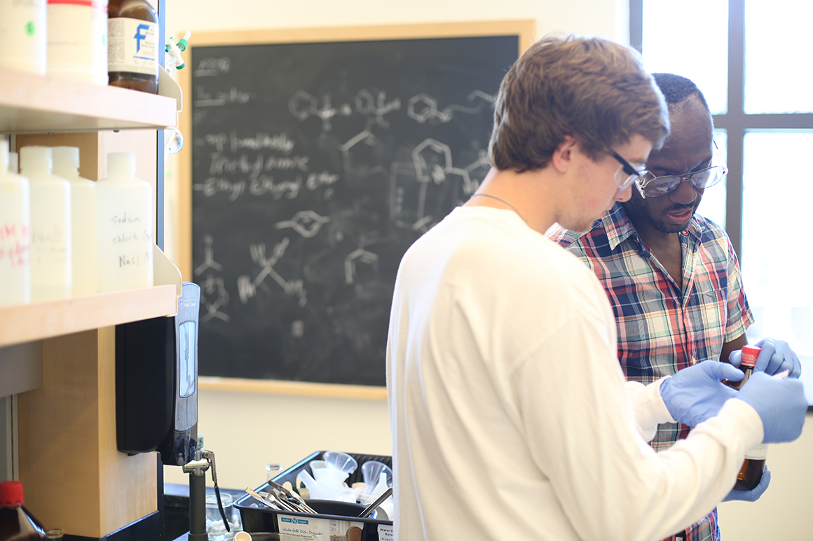 Andre Isaacs '05, assistant professor of chemistry, confers with a student during a lab.