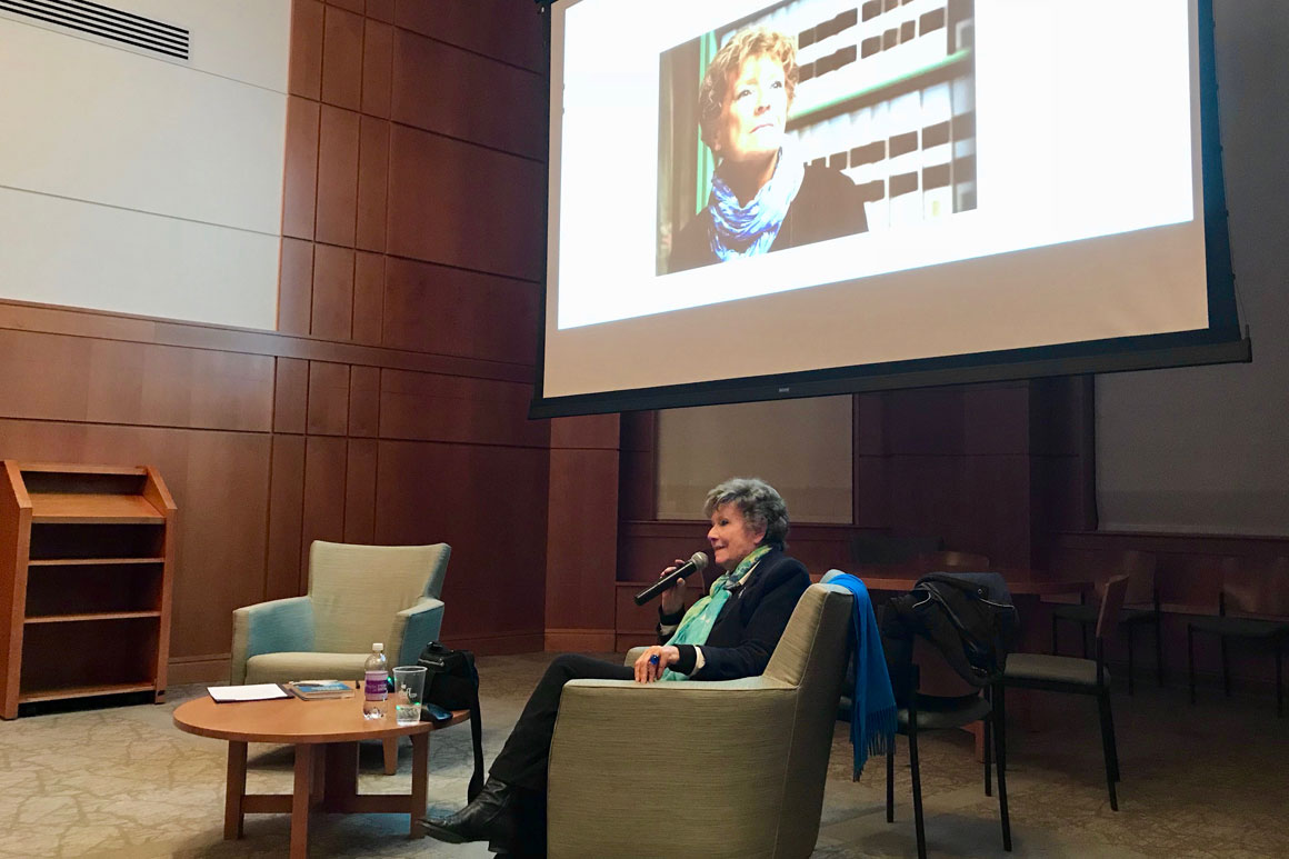 woman in a chair with a migrphone in front of a screen