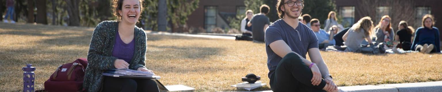 Happy students stilling on a wall outdoors.