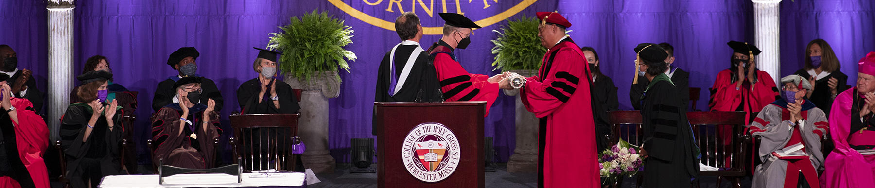 Rev. Philip L. Boroughs, former president of Holy Cross, hands the mace to Vincent D. Rougeau, new president of Holy Cross