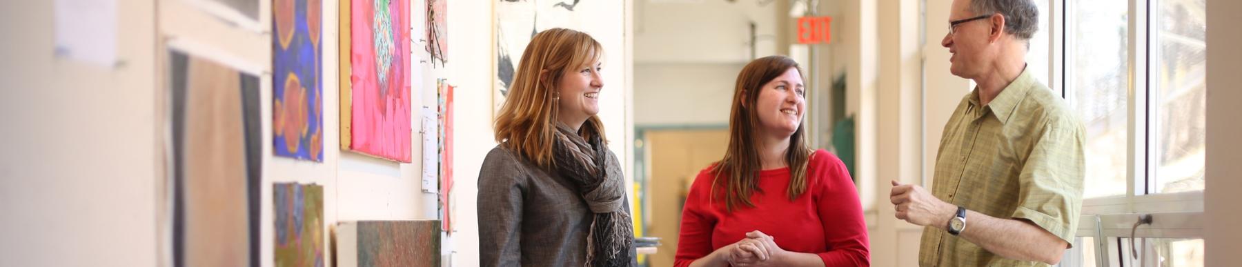 three faculty members standing and conversing