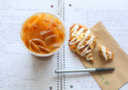 Iced coffee, scone and pen resting on an open notebook.