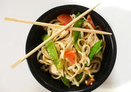 Bowl of stir fry with chopsticks resting on top of bowl