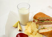 sandwich, slices of apple, potato chips and glass of milk