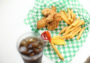 Several chicken fingers, french fries, honey mustard sauce, ketchup and glass of soda with ice.