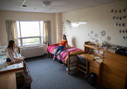 two students sitting on their beds chatting in their room in Loyola Hall