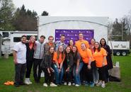 Group of students posing in front of a Holy Cross banner on a gray day.