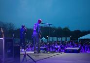 Picture of back of band playing on a stage outside in the evening