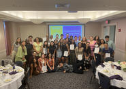 A group of students gathered before a screen in a conference room