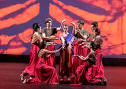 Jasmine 1 sings, surrounded by the company.