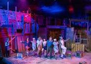 Family dances while Shen Te looks on.