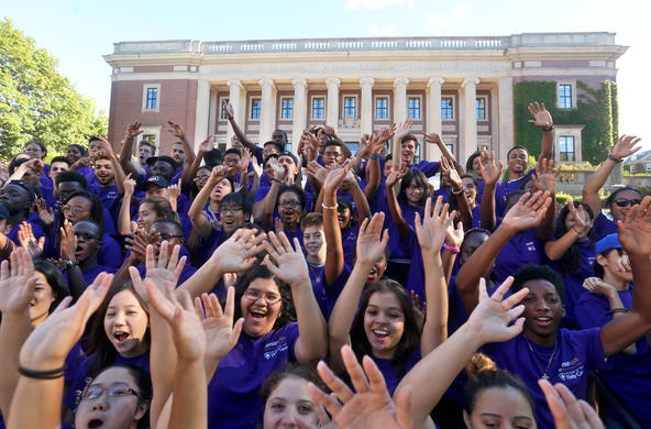 students in front of library waving their hands in the air