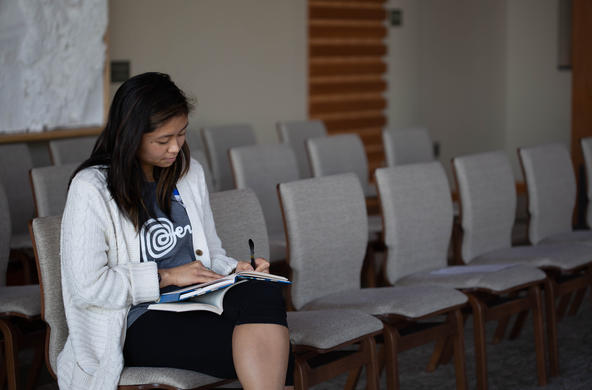 Student taking notes in a classroom.