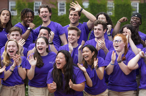 A group of students at orientation. They are standing next to each other clapping and laughing/cheering.