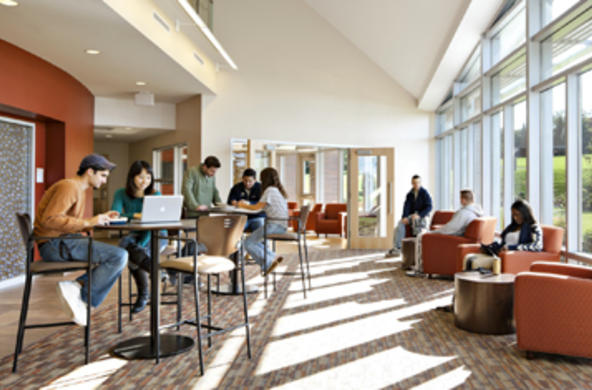students at tables and couches with laptops