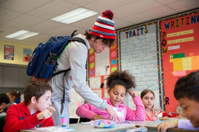 students working with younger students in a school classroom