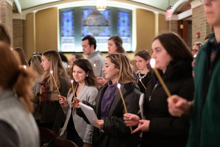 students holding candles at Mass
