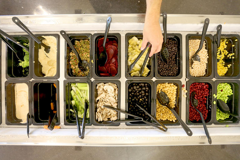 A student using tongs to reach for artichokes in a station of healthy food in Kimball Dining Hall.