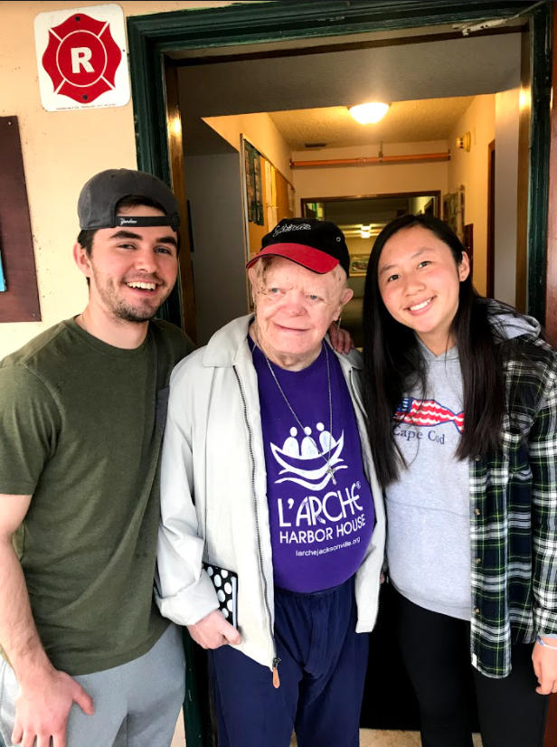 Two Holy Cross students standing beside a L'arche community member during an immersion program. 