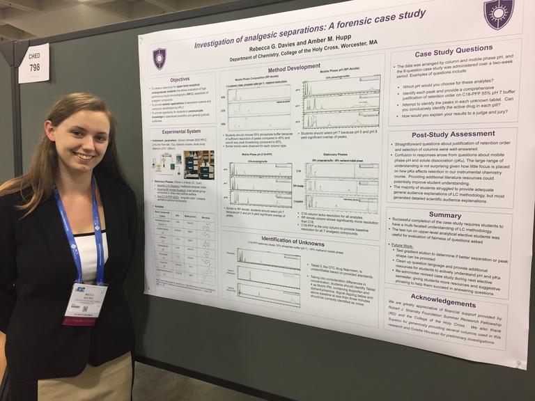 student at a conference standing beside her poster 