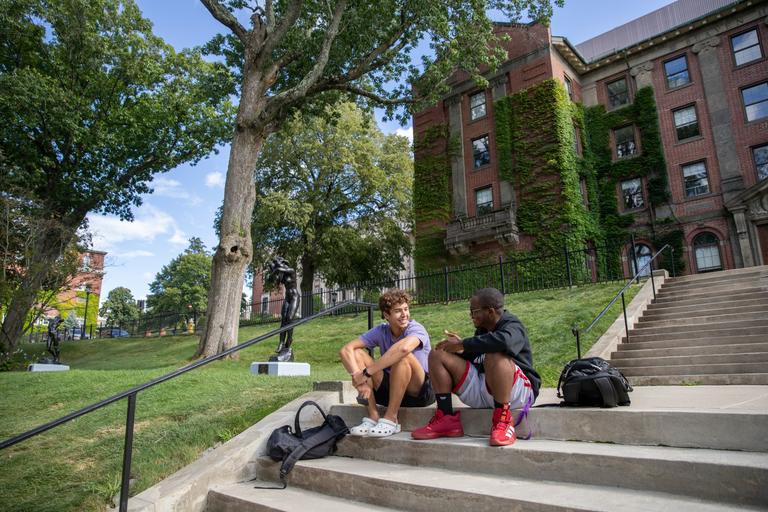 Two college students sitting on the steps having an engaging conversation.
