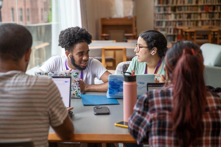Students in library sitting around a table with their laptops.