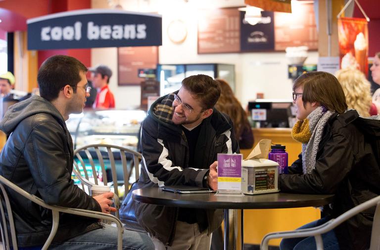 Students in a cafe sitting at a table talking.