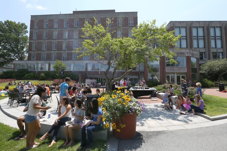 People gathered in a campus area on a sunny day.