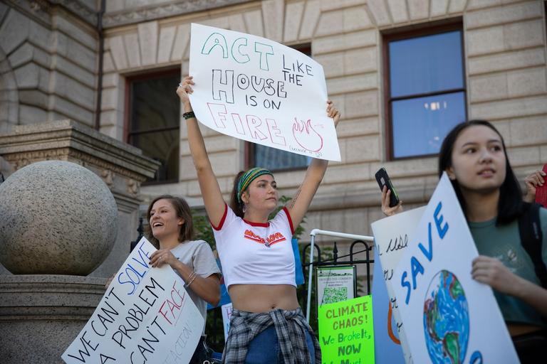 A young lady with 4 children smiling. Behind them is a dark but artful wall mural