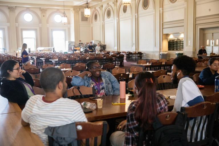 Students gathered in a room with a lot of tables and chairs