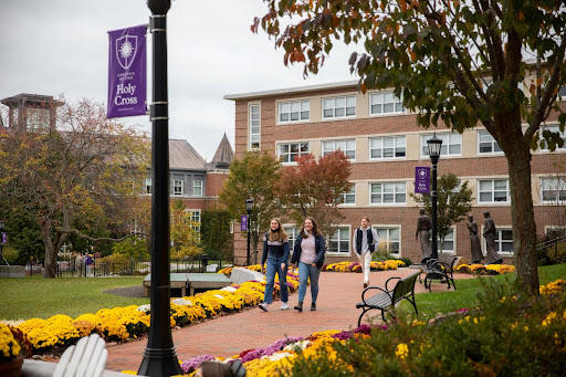 Image of a couple  students walking down a brick walkway outside on the Holy Cross campus.