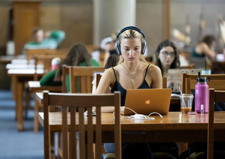 Student looking at a latpop with headphones on