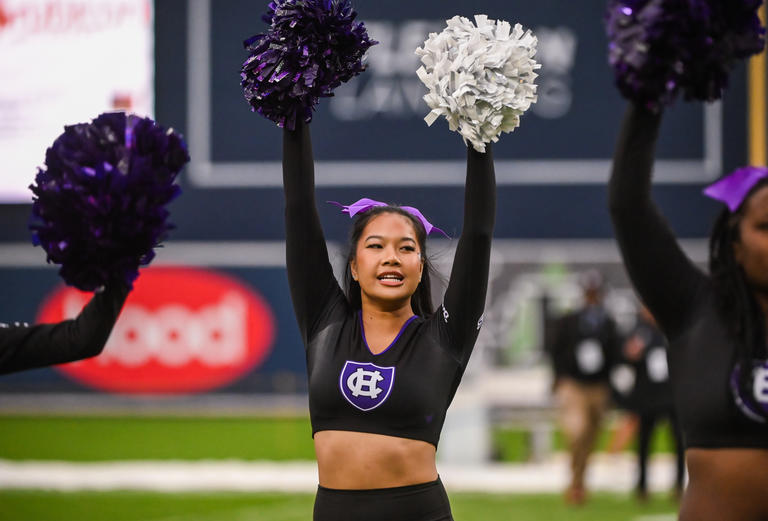 Holy Cross Cheerleader shaking pom-poms at a game