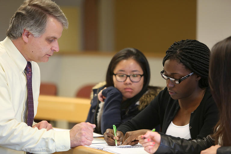 Professor and students working on papers at a table