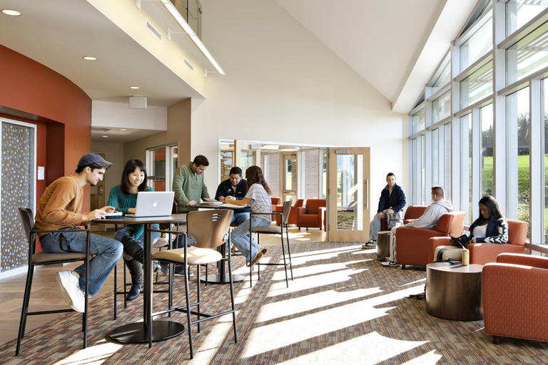 students sitting at high-top tables and couches on laptops