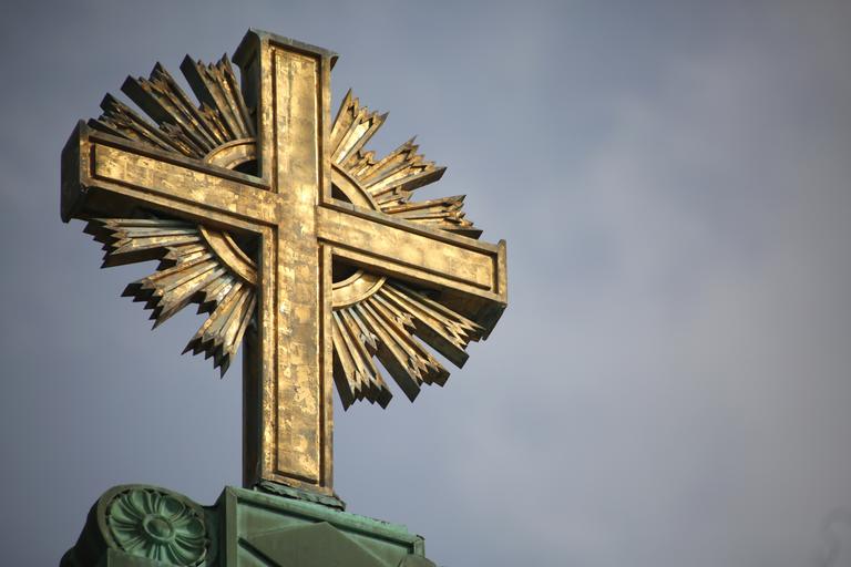 gold cross on top of okane