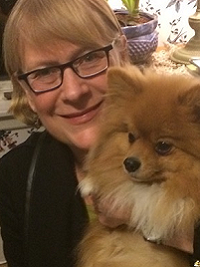 headshot of faculty with glasses and short light hair holding a dog