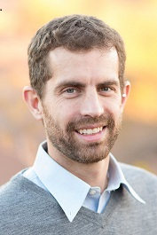 close up picture of man with light hair and beard with a grey sweater on