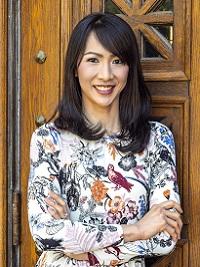 faculty member with floral dress standing in front of brown doors with her arms crossed and smiling