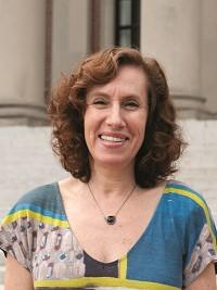 woman with shoulder length hair and green, blue, yellow pattered shirt