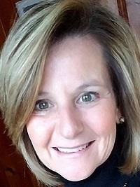 close up of a women with blond hair swept to the side smiling at the camera