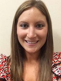 ashley isgro picture of a woman smiling at the camera with long brown hair and white background.