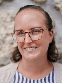 headshot of faculty member stone wall behind her smiling at the camera