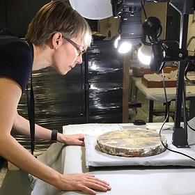 Professor Amanda Luyster examining a Chertsey tile while it is in a set up to be photographed.