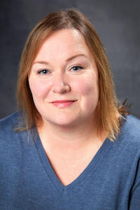 Headshot of Michelle Bata wearing a v neck blue sweater