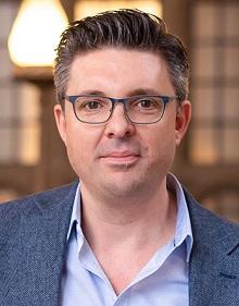 Headshot of Dr. William Purkis wearing glasses and blue shirt and blazer, looking into the camera.