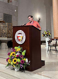 Man at lecturn adjusting microphone